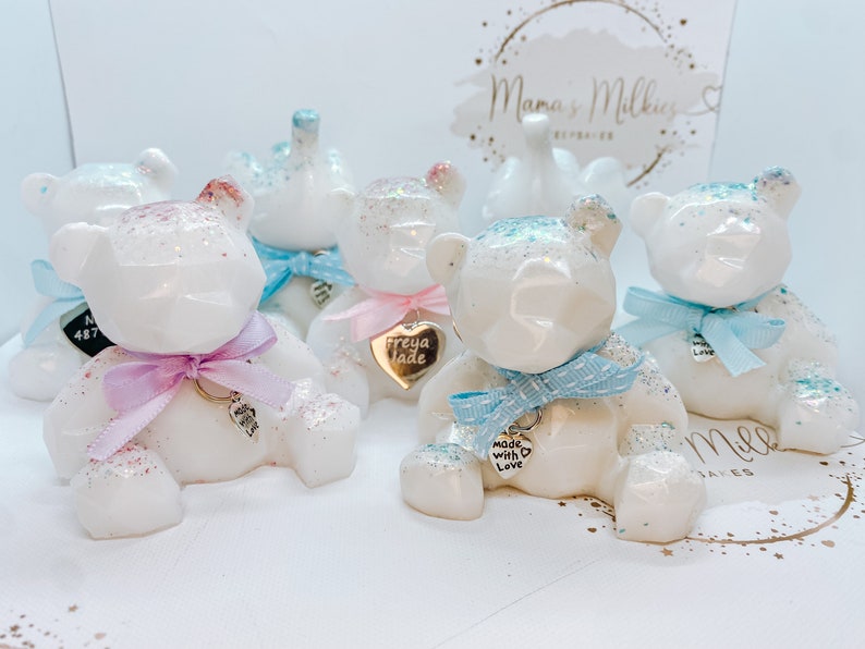 Op de afbeelding: Vijf witte keramische teddyberen met glitteraccenten. Elke beer heeft een zilveren charmeketting met een hartvormig label. De labels hebben verschillende inscripties, waaronder "Made with Love" en "Freya Jade".