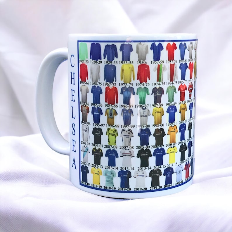 Puede incluir: Taza de cer&aacute;mica blanca con un dise&ntilde;o azul y blanco que presenta una l&iacute;nea de tiempo de las camisetas del Chelsea Football Club desde 1905 hasta 2021.