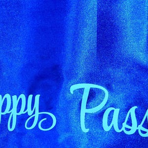 May include: Happy Passover written in light blue cursive on a bright blue background.