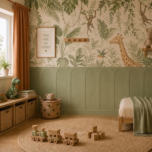 K&ouml;nnte beinhalten: Ein Kinderzimmer mit Dschungel-Tapete, salbeigr&uuml;ner Wandvert&auml;felung, einem h&ouml;lzernen Spielzeugeisenbahn-Set, einem geflochtenen Korb mit Teddyb&auml;r, einem gr&uuml;nen Dinosaurier-Stofftier und einem Rahmen mit dem Text YOU ARE SO LOVED.