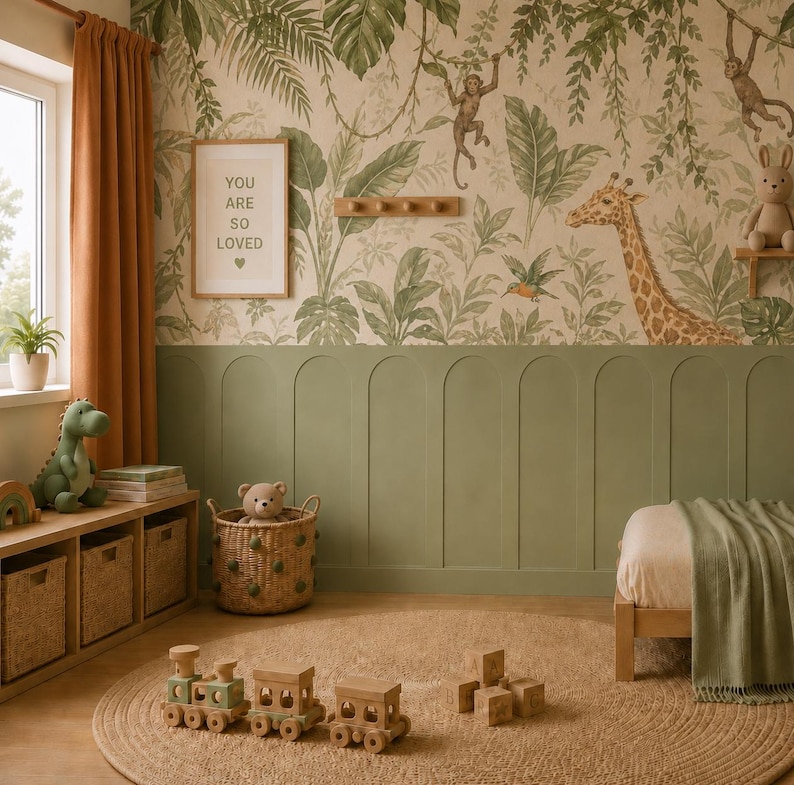 K&ouml;nnte beinhalten: Ein Kinderzimmer mit Dschungel-Tapete, salbeigr&uuml;ner Wandvert&auml;felung, einem h&ouml;lzernen Spielzeugeisenbahn-Set, einem geflochtenen Korb mit Teddyb&auml;r, einem gr&uuml;nen Dinosaurier-Stofftier und einem Rahmen mit dem Text YOU ARE SO LOVED.