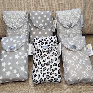Könnte beinhalten: Sechs kleine Stoffbeutel mit Klappverschlüssen. Die Muster variieren: Sterne, Punkte, Blumen und Leopardenmuster. Jeder Beutel hat einen Knopfverschluss und ein kleines Etikett. Die Farbpalette ist hauptsächlich grau und weiß.