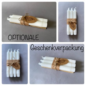 K&ouml;nnte beinhalten: Ein Set aus vier wei&szlig;en Stumpenkerzen, die mit Schnur und einem braunen Papieretikett zusammengebunden sind. Das Etikett hat ein schlichtes Federdesign und das Wort "OPTIONALE" steht unter den Kerzen.