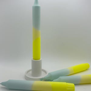 K&ouml;nnte beinhalten: Drei Ombre-Kerzen in einem Farbschema aus Hellblau, Creme und Gelb. Die Kerzen sind auf einer wei&szlig;en Oberfl&auml;che angeordnet. Eine Kerze befindet sich in einem wei&szlig;en Kerzenhalter.