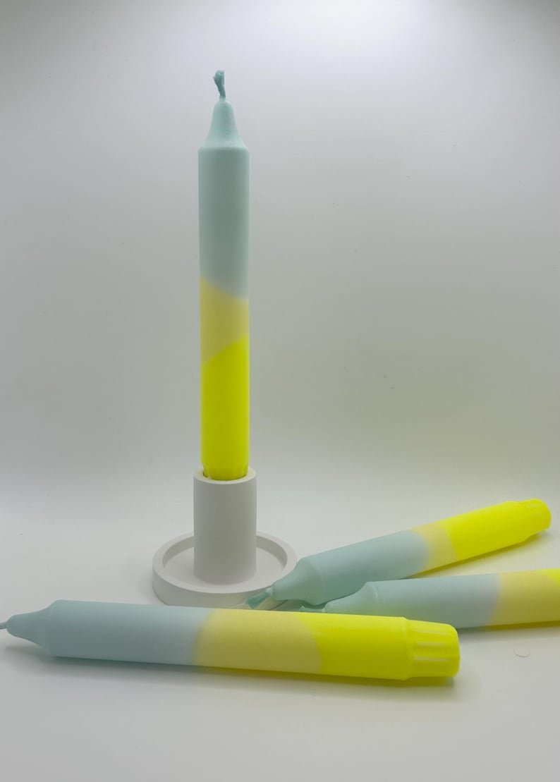 K&ouml;nnte beinhalten: Drei Ombre-Kerzen in einem Farbschema aus Hellblau, Creme und Gelb. Die Kerzen sind auf einer wei&szlig;en Oberfl&auml;che angeordnet. Eine Kerze befindet sich in einem wei&szlig;en Kerzenhalter.