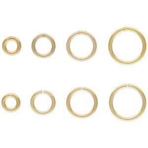 Könnte beinhalten: Sortiment von acht goldenen Sprungringen in verschiedenen Größen. Die Sprungringe sind rund und haben eine glatte Oberfläche.