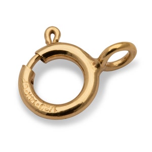Könnte beinhalten: Ein goldfarbener Metallverschluss mit einem runden Ring und einer kleinen Schlaufe. Der Verschluss ist mit "1/20 14K." gekennzeichnet.