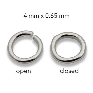 Könnte beinhalten: Zwei silberfarbene Sprungringe, einer offen und einer geschlossen, werden vor einem weißen Hintergrund gezeigt. Der offene Ring ist leicht getrennt, während der geschlossene Ring ein vollständiger Kreis ist. Text oben: "4 mm x 0,65 mm".