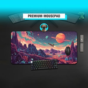 Puede incluir: Una alfombrilla de ratón premium con un diseño vibrante con temática espacial que presenta un planeta con anillos, una nave espacial y montañas coloridas. También se ven un teclado y un ratón negros.