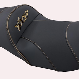 Pode incluir: Assento de motocicleta preto com costuras douradas e a palavra "Hornet" em letras douradas. O assento tem um design contornado para o conforto do motociclista e uma estética elegante e moderna.