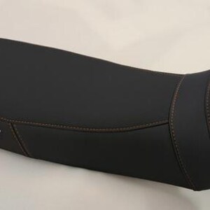 Op de afbeelding: Een zwarte motorzadel met bruine stiksels. De zadel heeft een gebogen ontwerp en is voorzien van de tekst "EMBROIDERY - HAFT" in het wit. De zadel is ontworpen voor comfort en ondersteuning tijdens lange ritten.