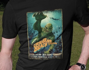 May include: Black t-shirt with a vintage movie poster print of "Creature from the Black Lagoon". The poster features a green, scaly creature with sharp teeth and claws, emerging from the water. The text on the poster reads "Creature from the Black Lagoon" in a bold, yellow font.