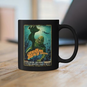 May include: Black coffee mug with a vintage movie poster design featuring a green creature from the black lagoon. The poster text reads "Creature from the Black Lagoon".
