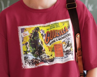 May include: A red t-shirt with a vintage Godzilla movie poster print. The poster features a large green monster with the text "An Enraged Monster Wipes Out An Entire City! Godzilla King of the Monsters!"