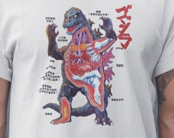 May include: A white t-shirt with a graphic of Godzilla's anatomy labeled in Japanese. The graphic shows Godzilla's internal organs, bones, and muscles.