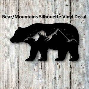 May include: Black silhouette vinyl decal of a bear standing in front of a mountain range with a moon and stars in the background.
