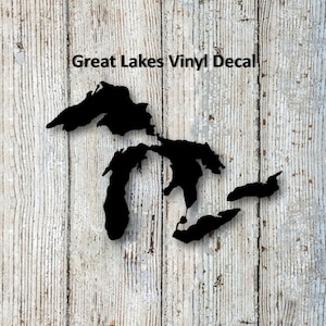 May include: Black vinyl decal of the Great Lakes on a white wood background. The decal is a silhouette of the Great Lakes, with the text "Great Lakes Vinyl Decal" above the image.