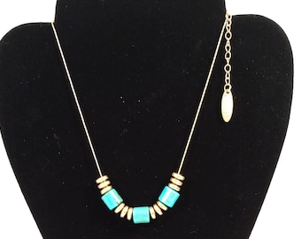 Collar de cadena en tono dorado con diseño de Plunder con cuentas verde azulado y detalles dorados.