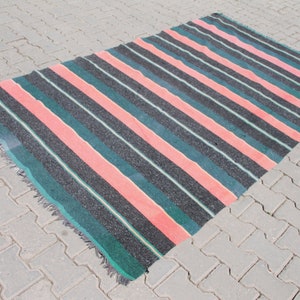 May include: A striped rug with pink, green, and black stripes. The rug has a fringed edge.