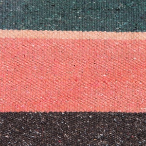 May include: Close-up of a woven fabric with three horizontal stripes. The top stripe is dark green, the middle stripe is pink, and the bottom stripe is dark brown.