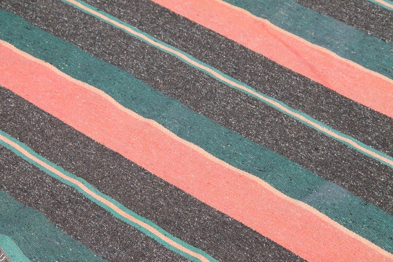 May include: A close-up of a striped fabric with alternating bands of black, teal green, and coral pink.