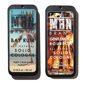 May include: Two rectangular solid cologne tins. One features a beach scene with text "BAY RUM" and "KEEP CALM AND PARLEY". The other has a bourbon image with "GENTLEMEN'S BOURBON" and "JUST A LIL OLD FASHIONED". Each tin is 0.75 fl oz / 22 ml.