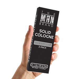 May include: A black box with white text that reads "The Man Brand Solid Cologne Variety Pack 3 Pack". The box also includes the text "3 - 1 oz / 30 ml Tins Net Weight - 3 oz (85 g)".