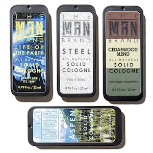 May include: Five rectangular solid cologne tins from The Man Brand. The tins feature various labels: "Life of the Party," "Steel," "Cedarwood Blend," and "Aspen." Each tin is 0.75 fl oz / 22 ml.