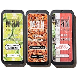 May include: Three rectangular solid cologne tins. The tins are black with the text "THE MAN BRAND" and "SOLID COLOGNE". Scents include Bergamot & Cedar, Sandalwood, and Sweet Tobacco. Each tin contains 0.75 oz / 22 ml.