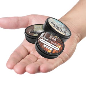 May include: Three small round metal tins of solid cologne. The tins are black with white lettering and feature different scents: Woodsman, Bay Rum, and Gentlemen's Bourbon. Each tin contains 1 ounce (30 ml) of cologne.