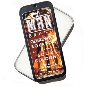 May include: A black rectangular tin containing solid cologne. The label reads "THE MAN BRAND GENTLEMEN'S BOURBON ALL NATURAL SOLID COLOGNE". The cologne is "JUST A LIL OLD FASHIONED" and is 0.75 fl oz / 22 ml.