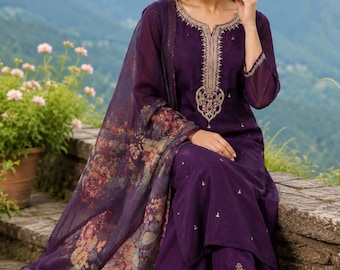 May include: A deep purple three-piece outfit consisting of a long-sleeved tunic with gold embroidery around the neckline, matching straight-leg trousers with embroidered hems, and a sheer purple dupatta featuring a colourful floral print.