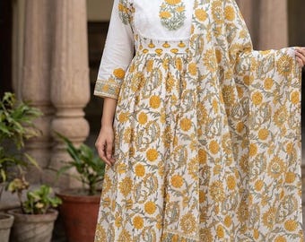 May include: A white and yellow floral print dress with a matching scarf. The dress has a round neckline and three-quarter sleeves. The floral pattern is yellow on a white background. The scarf is draped over the shoulder.