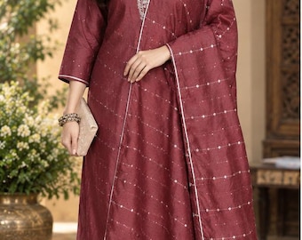 May include: A deep maroon three-piece outfit consisting of a long-sleeved tunic with a notched neckline featuring silver embroidery, wide-leg trousers, and a matching dupatta. The fabric has a subtle sheen with thin, diagonal silver dotted lines.