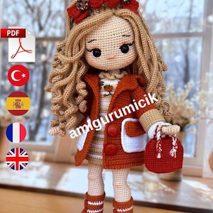 Può includere: Una bambola all'uncinetto con lunghi capelli biondi ricci, che indossa un cappotto color ruggine con due grandi bottoni, un vestito a righe bianche e beige e stivali color ruggine abbinati. La bambola ha un accessorio rosso e una borsa rossa.