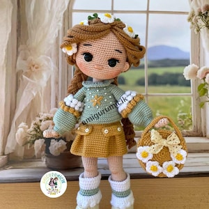 May include: A handmade crochet doll with brown hair adorned with a daisy crown. The doll wears a green sweater, a yellow skirt, and white boots. It holds a small basket decorated with daisies and a bow. The doll is standing in front of a window.