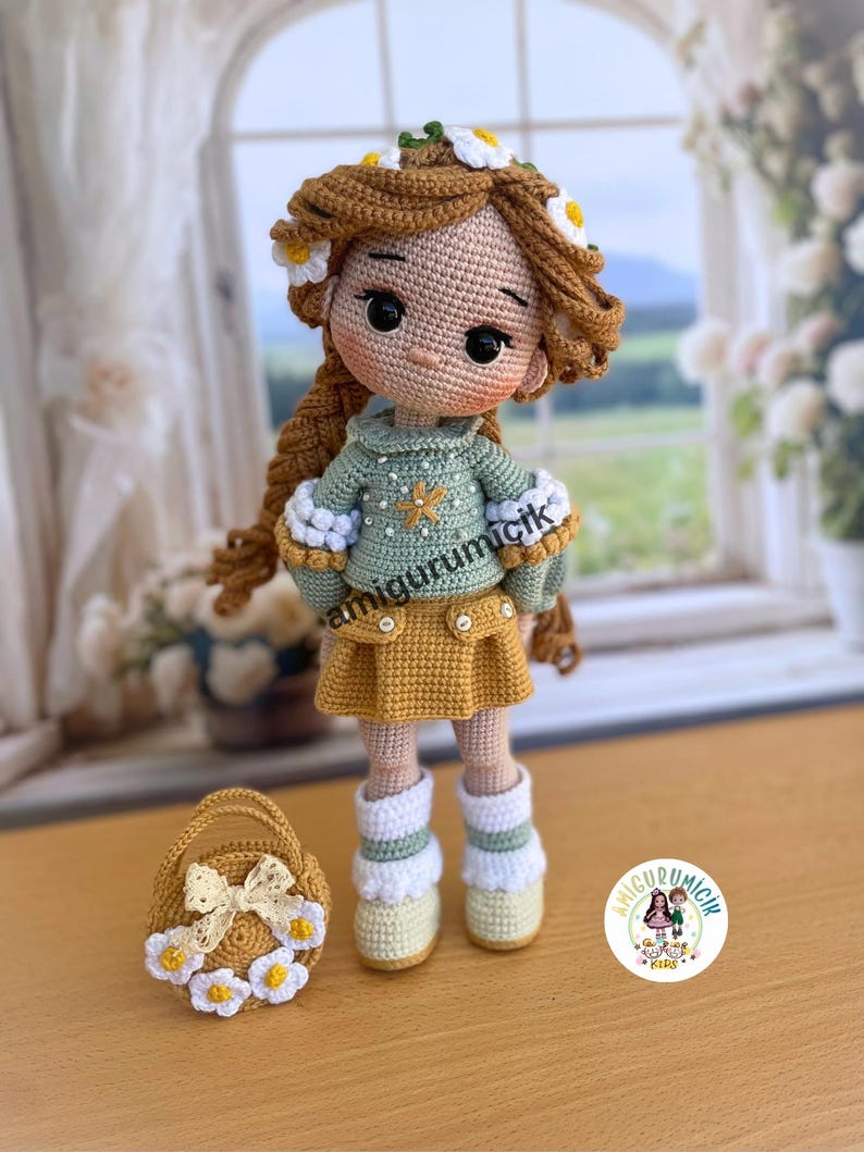 May include: A handmade crochet doll with brown hair adorned with a daisy crown. The doll wears a green sweater, yellow skirt, and white boots. A small basket with a bow and daisy accents sits beside the doll. The doll's name is "amigurumicik".