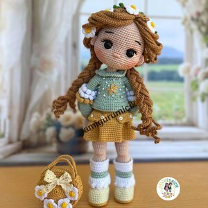 May include: Crocheted doll with long brown braids, wearing a green sweater, yellow skirt, and white socks. The doll has a floral crown and is holding a small matching purse. The text "amigurumicik" is visible.