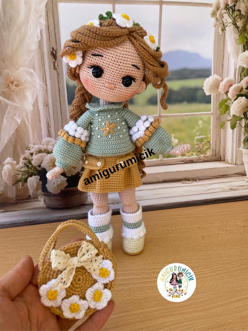 May include: A handmade crochet doll with long brown hair adorned with white and yellow daisy accents. The doll wears a green sweater, a mustard-colored skirt, and white boots. A small basket with daisy embellishments and a bow is also present.