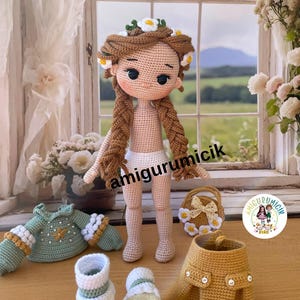 May include: A handmade crochet doll with long brown braids and a floral crown. The doll is surrounded by crochet clothing items, including a green sweater, a yellow skirt, and shoes. A small crochet purse is also present.