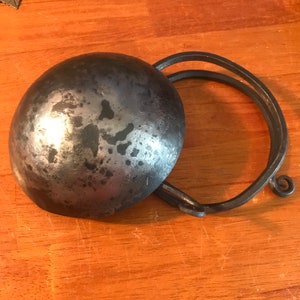 May include: A silver metal bowl with a hammered finish and a matching metal handle. The bowl is slightly dented and has a rustic look.