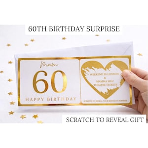 May include: A white birthday card with gold foil accents. The card reads "60th Birthday Surprise" and "Happy Birthday." The card features a scratch-off area revealing "Weekend in London & Mamma Mia! Theatre Tickets."