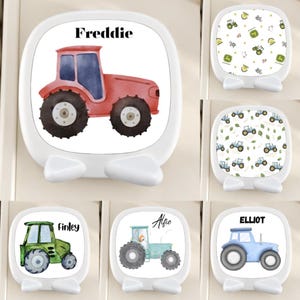 May include: A collection of white, square-shaped, rounded-corner tabletop mirrors featuring various tractor illustrations and personalized names including Freddie, Finley, Alfie, and Elliot, alongside patterns of small tractors and farm-themed icons.