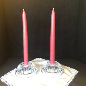 May include: Two clear glass candle holders with a decorative cut-glass design. Each holder has a burgundy candle.