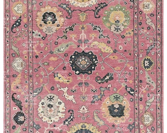 May include: A pink and cream area rug with a traditional Persian design. The rug features intricate floral patterns, geometric shapes, and a central medallion. The rug has a fringed border.