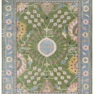 May include: A rectangular green rug with a central floral design and a blue border. The rug features a symmetrical pattern with pink, yellow, and blue accents. The text "CRAFTSMAN RUGS DECOR THE HOME" is visible.