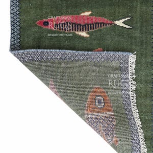 K&ouml;nnte beinhalten: Gr&uuml;ner Teppich mit Fischmuster. Der Teppich zeigt rote und schwarze Fischdesigns auf gr&uuml;nem Hintergrund. Der Teppich hat einen blauen Rand und den Text "CRAFTSMAN RUGS DECOR THE HOME".