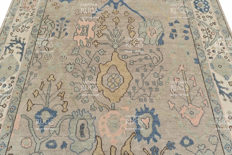 May include: A close-up of a beige rug with an elaborate floral design. The pattern includes blue, pink, and yellow elements. The rug's border has a matching pattern, enhancing the overall look. This rug is suitable for home decor and measures in centimeters.