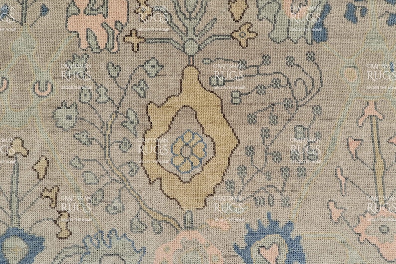 May include: Close-up of a beige rug with a detailed floral pattern. The design features a central yellow motif surrounded by blue, pink, and green floral elements. The rug has a vintage, distressed appearance.