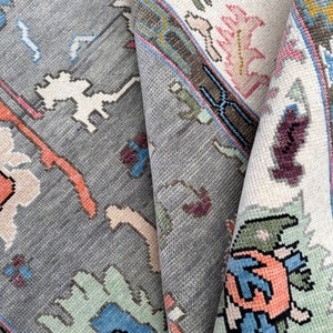 May include: A close-up of a gray and white rug with a colorful geometric pattern. The rug has a faded, vintage look and is made of wool.